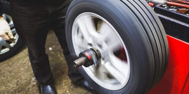 mechanic aligning car tire at service